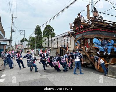 14 juillet 2023, Japon, Sawara : sur des roues en bois massives et accompagnées de musique traditionnelle de flûte et de tambour, des centaines de Japonais tirent de puissants chars à travers une ancienne ville commerçante au Grand Festival de Sawara, l'un des plus grands festivals folkloriques de la région de Kanto autour de Tokyo. Au début des trois jours du Grand Festival de Sawara, les participants au festival habillés en costumes traditionnels poussaient et tiraient les flotteurs «dashi» en bois décoré, sur lesquels de précieuses figures de divinies, de célèbres samouraïs ou même des animaux ont été intronisés, chantant joyeusement à travers les ruelles de la vieille ville d Banque D'Images