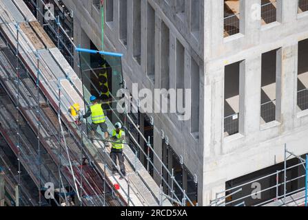 Vitrier installant des fenêtres sur un bâtiment commercial. Banque D'Images