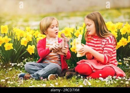 Petits enfants mignons, grande sœur et petit frère, avec des lapins de Pâques en chocolat célébrant la fête traditionnelle. Famille, vacances, printemps, enfant insouciant Banque D'Images