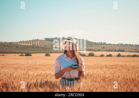 Une fille avec un appareil photo vintage debout dans un champ de blé Banque D'Images