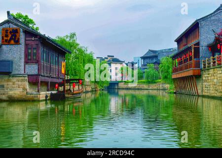 Découvrez le mélange harmonieux d'une belle rivière, d'arbres verdoyants et de maisons traditionnelles se prélassant dans l'étreinte douce de la lumière du soleil. Banque D'Images