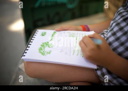 Fille de huit ans peignant et dessinant dans un parc. Banque D'Images