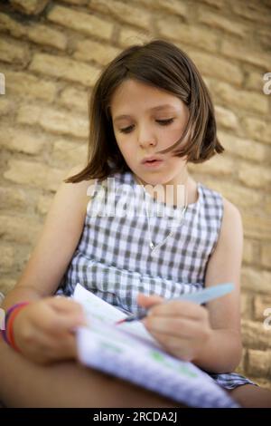 Fille de huit ans peignant et dessinant dans un parc. Banque D'Images