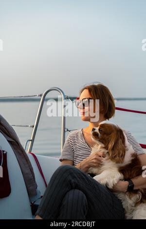 Jeune femme sur un yacht avec un chien, cavalier King Charles Spaniel Banque D'Images
