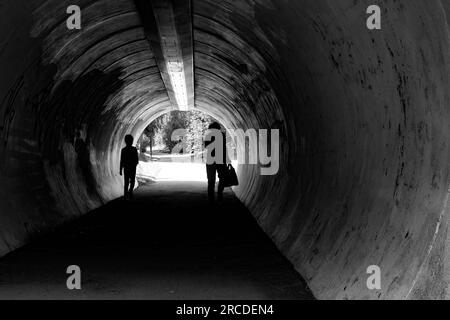 Grand-mère et enfant dans des silhouettes dans le tunnel avec chien en attente de l'autre côté. Banque D'Images