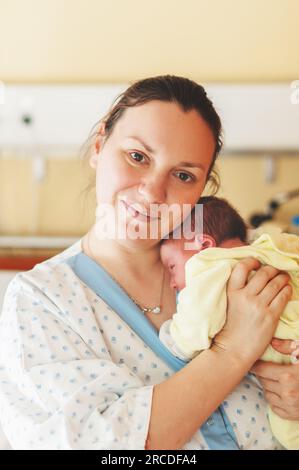 Jeune mère heureuse et fatiguée avec le nouveau-né à l'hôpital après l'accouchement Banque D'Images