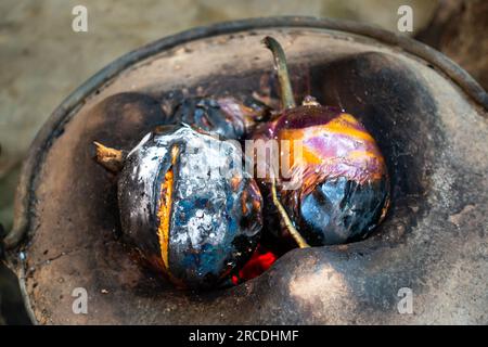 Aubergine rôtie entière ou brinjal dans un poêle en argile traditionnel, Angeethi dans le nord de l'Inde. Préparation d'une cuisine nord-indienne, Baigan ka Bharta. Po Banque D'Images