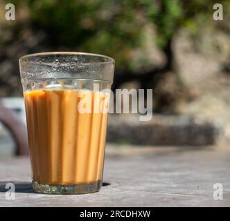 Gros plan d'un thé au lait dans un verre transparent traditionnel. Road Side place ou Tapri en Inde. Banque D'Images