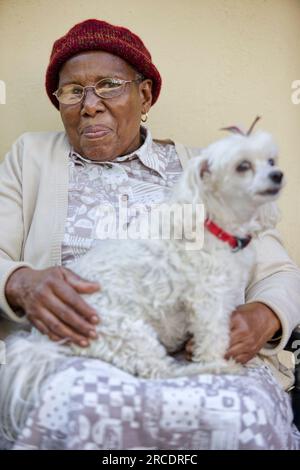 vieille dame africaine en retraite tenant son chien maltais bien-aimé Banque D'Images