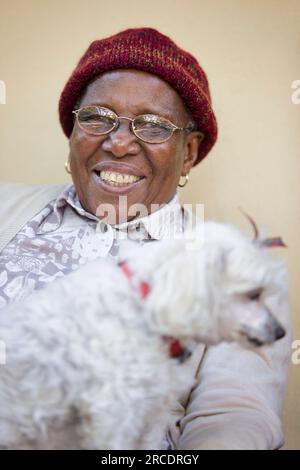 vieille dame africaine en retraite tenant son chien maltais bien-aimé Banque D'Images