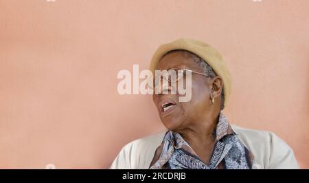 vieille dame africaine à la retraite située dans une chaise dans sa cour en face de la maison Banque D'Images