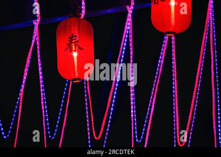 lanternes chinoises en papier rouge avec des cordes lumineuses dans la nuit, éclairées à l'étranger par la communauté expatriée Banque D'Images