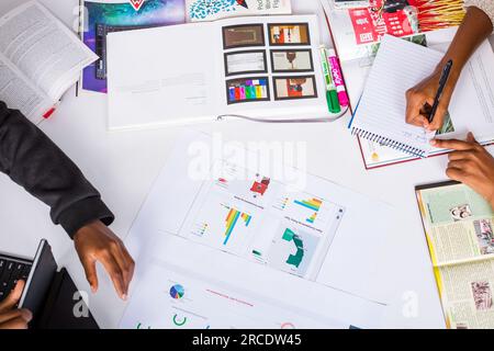 Les mains touchant les illustrations du tableau des tartes à plat reposent sur la table des discussions en table ronde Banque D'Images