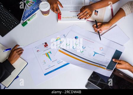 Les mains touchant les illustrations du tableau des tartes à plat reposent sur la table des discussions en table ronde Banque D'Images