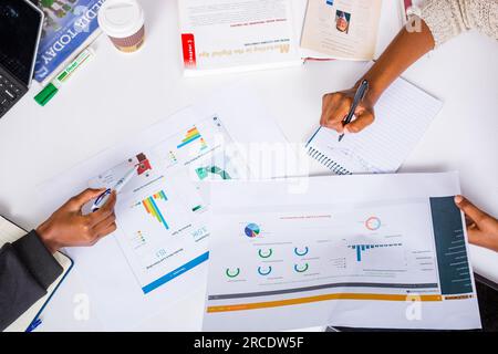 Les mains touchant les illustrations du tableau des tartes à plat reposent sur la table des discussions en table ronde Banque D'Images