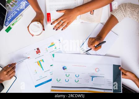Les mains touchant les illustrations du tableau des tartes à plat reposent sur la table des discussions en table ronde Banque D'Images