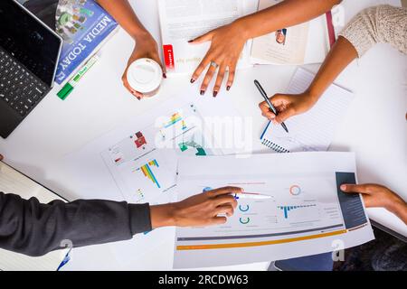 Les mains touchant les illustrations du tableau des tartes à plat reposent sur la table des discussions en table ronde Banque D'Images