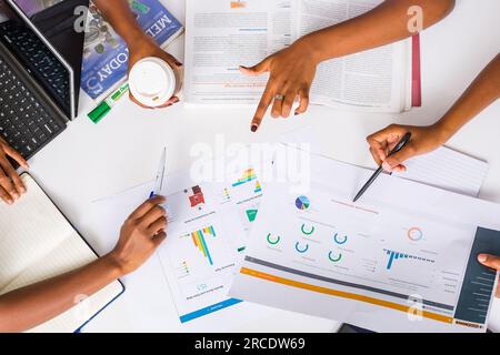 Les mains touchant les illustrations du tableau des tartes à plat reposent sur la table des discussions en table ronde Banque D'Images