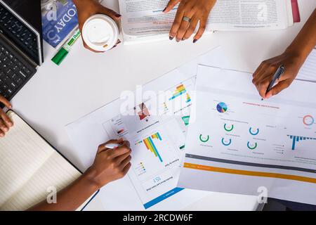 Les mains touchant les illustrations du tableau des tartes à plat reposent sur la table des discussions en table ronde Banque D'Images