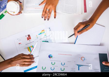 Les mains touchant les illustrations du tableau des tartes à plat reposent sur la table des discussions en table ronde Banque D'Images