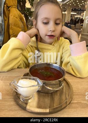 L'enfant mange de la soupe borscht avec de la crème sure Banque D'Images