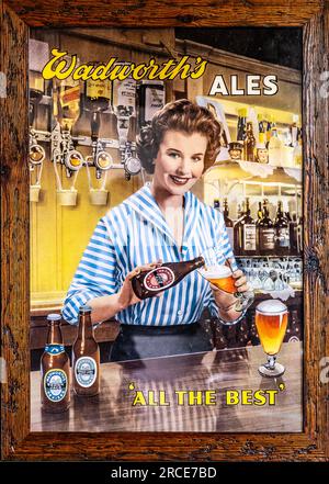 Affiche publicitaire de bière vintage Wadworth barmaid verre versant de bouteille, Wiltshire, Angleterre, Royaume-Uni Banque D'Images
