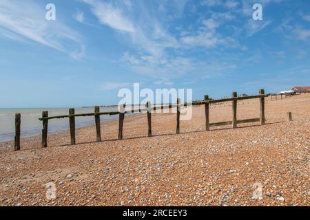 Nuages blancs chuchotés du soir au-dessus des grands groynes sur la plage de Pevensey Bay Banque D'Images