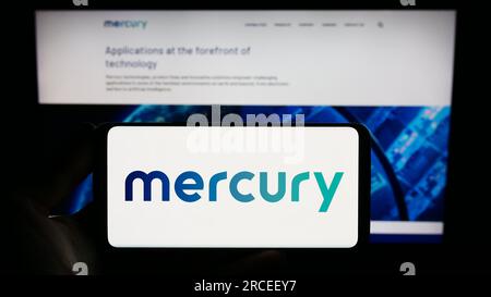 Personne tenant un smartphone avec le logo de la société de défense américaine Mercury Systems Inc. Sur l'écran devant le site Web. Concentrez-vous sur l'affichage du téléphone. Banque D'Images