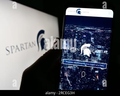 Personne tenant un téléphone portable avec le site Web de la société américaine Spartan Capital Securities LLC sur l'écran devant le logo. Concentrez-vous sur le centre de l'écran du téléphone. Banque D'Images