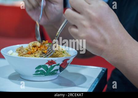 Gros plan de deux mains Préparez-vous à manger Mie Ayam ou un plat indonésien populaire composé de nouilles de poulet savoureuses et savoureuses. Photographie culinaire. Banque D'Images