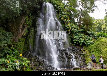 Cascade dans le jardin botanique de Ribeira do Guilherme dans le Nordeste avec des touristes, île Sao Miguel aux Açores. Banque D'Images