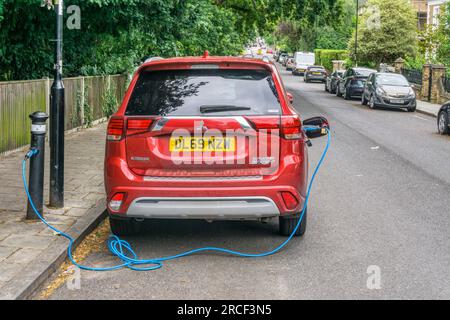 Voiture hybride rechargeable Mitsubishi Outlander PHEV à travers le trottoir à partir d'une borne Ubitricity & Siemens SimpleSocket dans une rue résidentielle. Banque D'Images