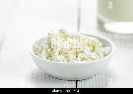 Soucoupe avec fromage cottage et un verre de lait sur une table en bois blanc. Style rustique. Banque D'Images