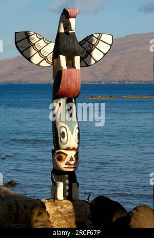 Totem regardant des canoës-balançoires au loin sur l'île hawaïenne de Maui. Banque D'Images