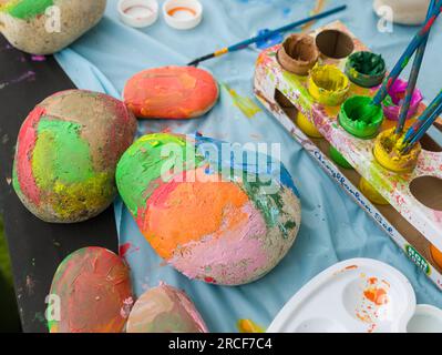 Pierres et cailloux aux couleurs vives peints par des enfants à l'aide de peinture acrylique. Banque D'Images