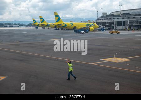 Medellin, Antioquia, Colombie - 23 octobre 2022 : le contrôleur de la circulation aérienne avec un gilet jaune fluorescent descend la piste de l'aéroport avec des Cros Orange Cones Banque D'Images