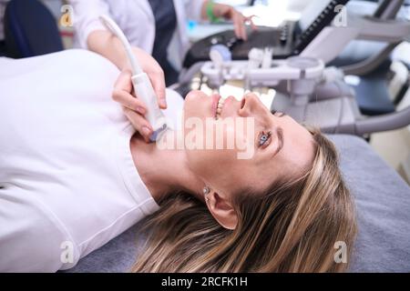 Femme agréable à la clinique pour l'échographie de la glande thyroïde Banque D'Images