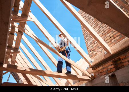 Femme chef architecte grimpant sur la construction en bois de toit pour vérifier la qualité Banque D'Images