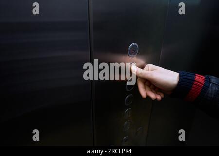 Un homme dans la cabine de l'ascenseur passager appuie sur le bouton de sélection du plancher Banque D'Images