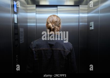 Homme dans une veste en denim est dans la cabine d'ascenseur de passagers Banque D'Images