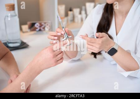 Docteur cosmétologue tient la seringue avec la substance rajeunissante dans ses mains Banque D'Images