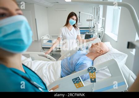 Les thérapeutes personnalisent l'équipement médical près du patient sur le lit dans la chambre Banque D'Images