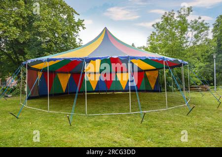 Petite tente de cirque colorée avec un poteau debout à moitié ouvert sur une prairie pour une fête d'été ou un festival, espace de copie, foyer sélectionné Banque D'Images