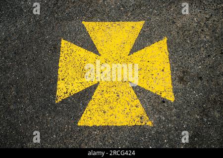 Croix maltaise jaune, aire de stationnement pour ambulance marquée du symbole jaune. Banque D'Images