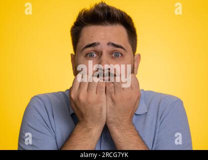 Homme caucasien déprimé stressé terrifié par les problèmes de danger, souffrant de phobie, trouble anxieux, exprime la peur, saluant non, insécurité, stress, panique. Jeune gars isolé sur fond de studio jaune Banque D'Images