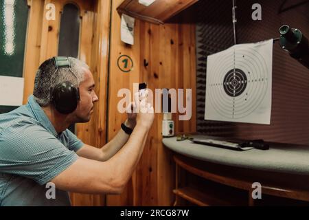 Un homme dans un stand de tir prend une photo et examine les résultats après la prise de vue Banque D'Images