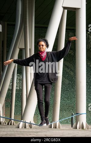 Femme colombienne portant un pantalon noir et un T-shirt marche sur une corde bleue pratiquant Slack Line Banque D'Images