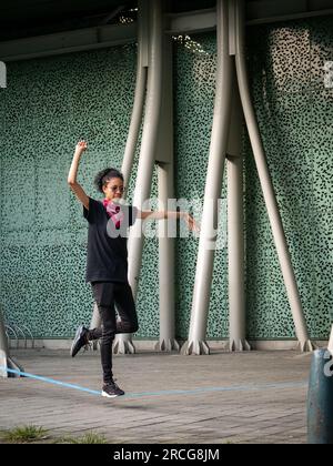 Femme colombienne portant un pantalon noir et un T-shirt marche sur une corde bleue pratiquant Slack Line Banque D'Images