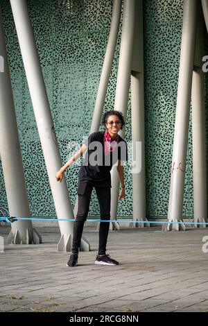 Femme colombienne portant un pantalon noir et un T-shirt chutes de la corde bleue pratiquant Slack Line Banque D'Images