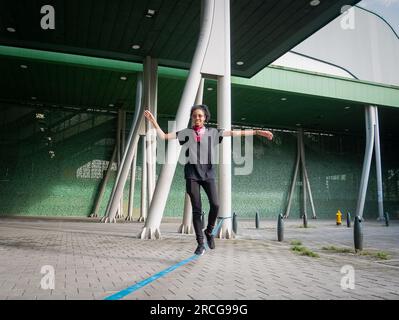 Femme colombienne portant un pantalon noir et un T-shirt marche sur une corde bleue pratiquant Slack Line Banque D'Images